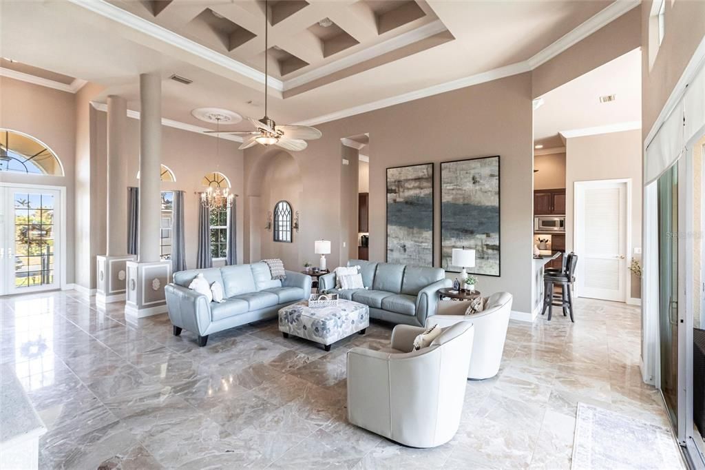 Exquisite living room is highlighted by 10' coffered ceilings, elegant columns, crown molding, and large windows with pool and canal views.