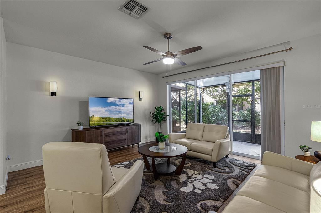 Large living room with triple wide sliding doors that lead to the screened, covered lanai