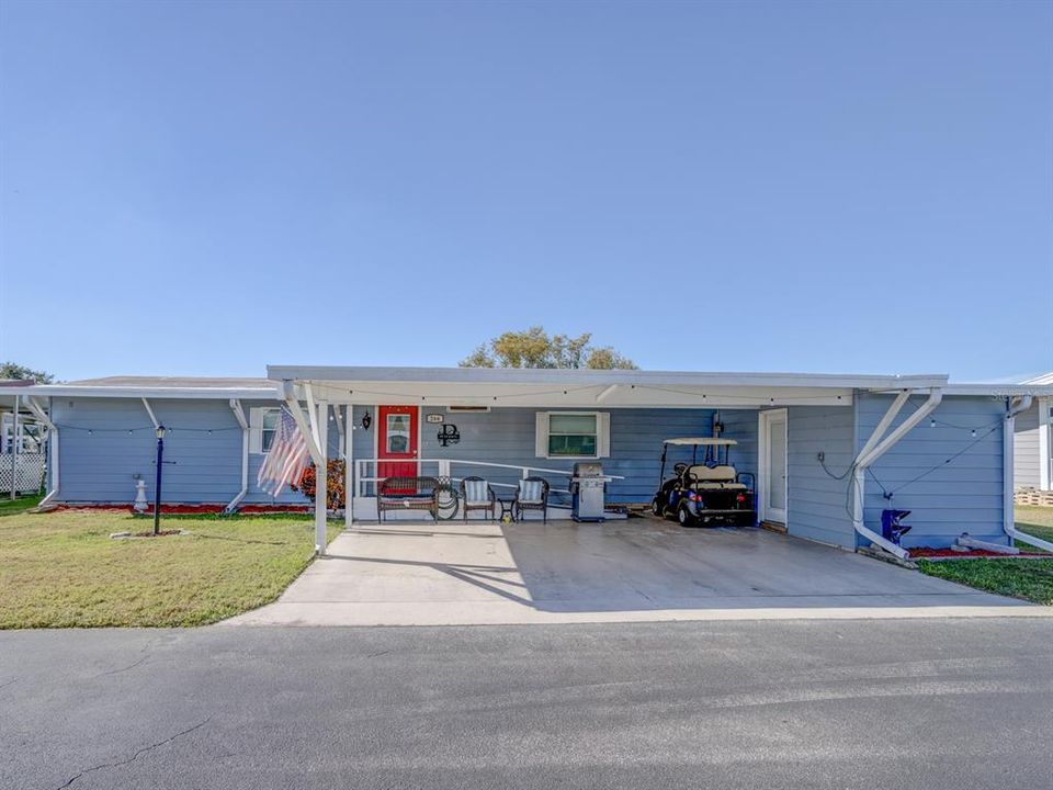 Front of the home with a large carport and separate shed to the right.