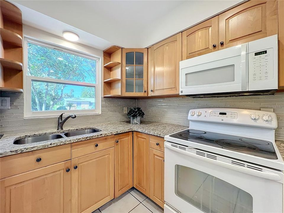 Beautifully updated kitchen featuring a tiled backsplash and stone countertop.