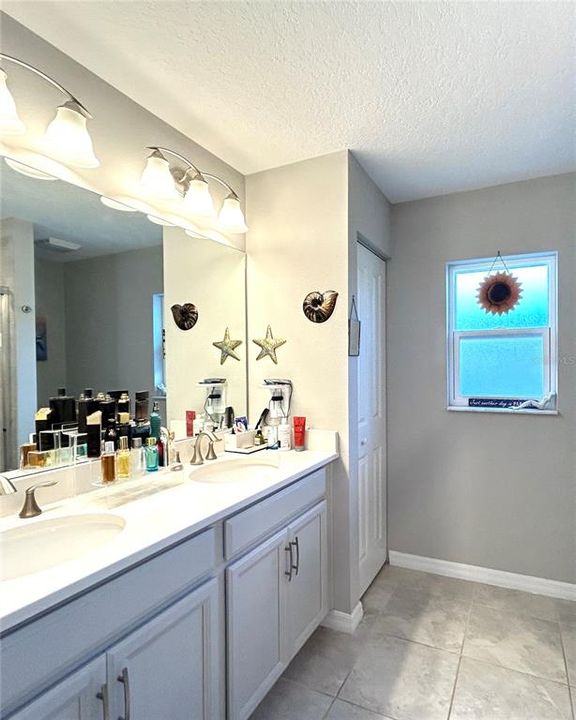 Primary bathroom with raised double sink vanity, linen closet and a a window