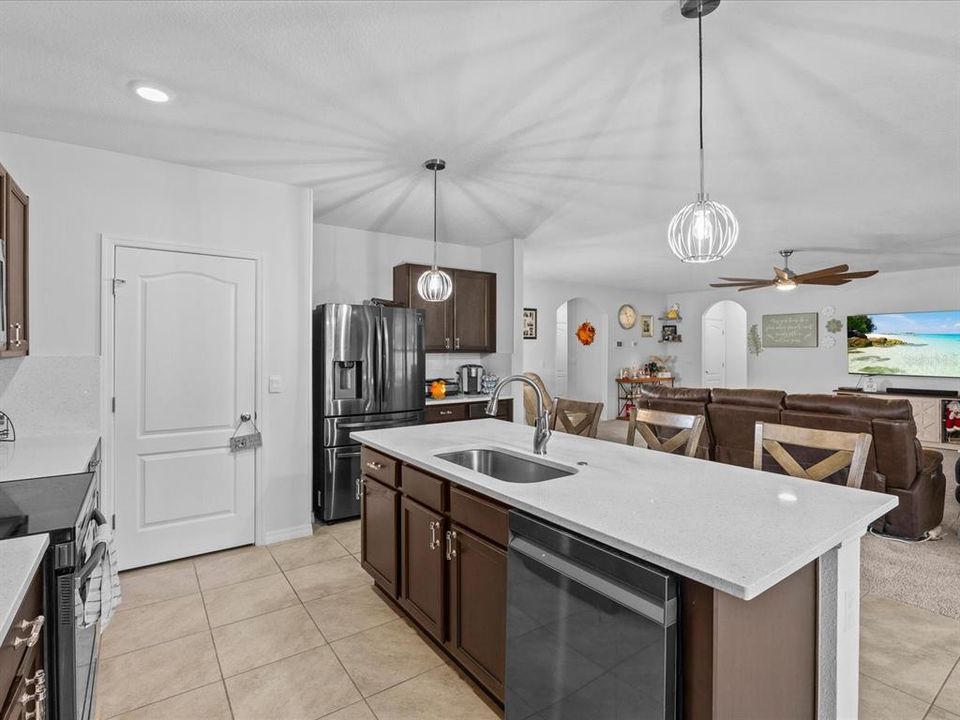 Kitchen with granite countertops, solid wood cabinets and decorative light fixtures with a view into the living room