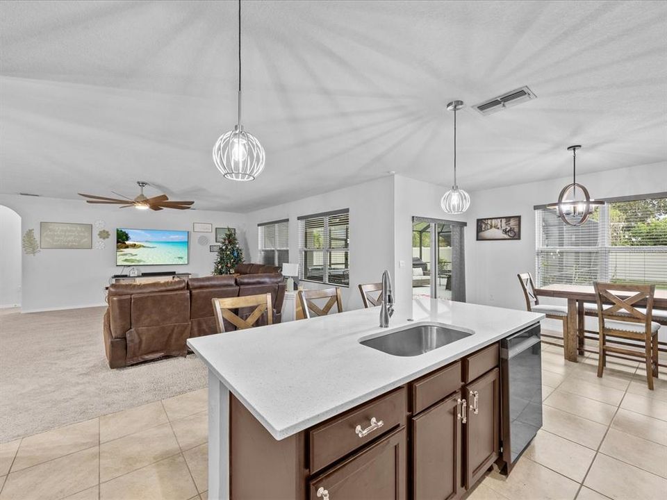 Kitchen with granite countertops, solid wood cabinets and decorative light fixtures with a view in to the breakfast nook and living room