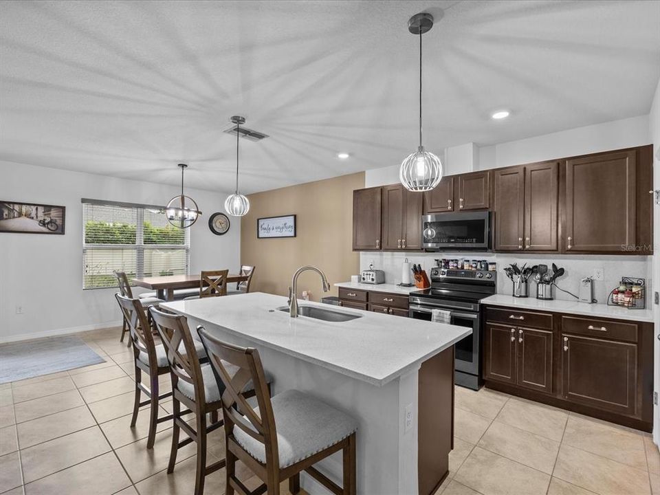 Kitchen with granite countertops, solid wood cabinets and decorative light fixtures with view into the breakfast nook