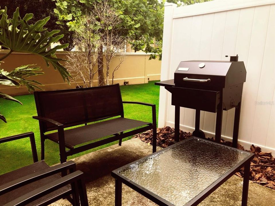 Private backyard with patio furniture and a grill