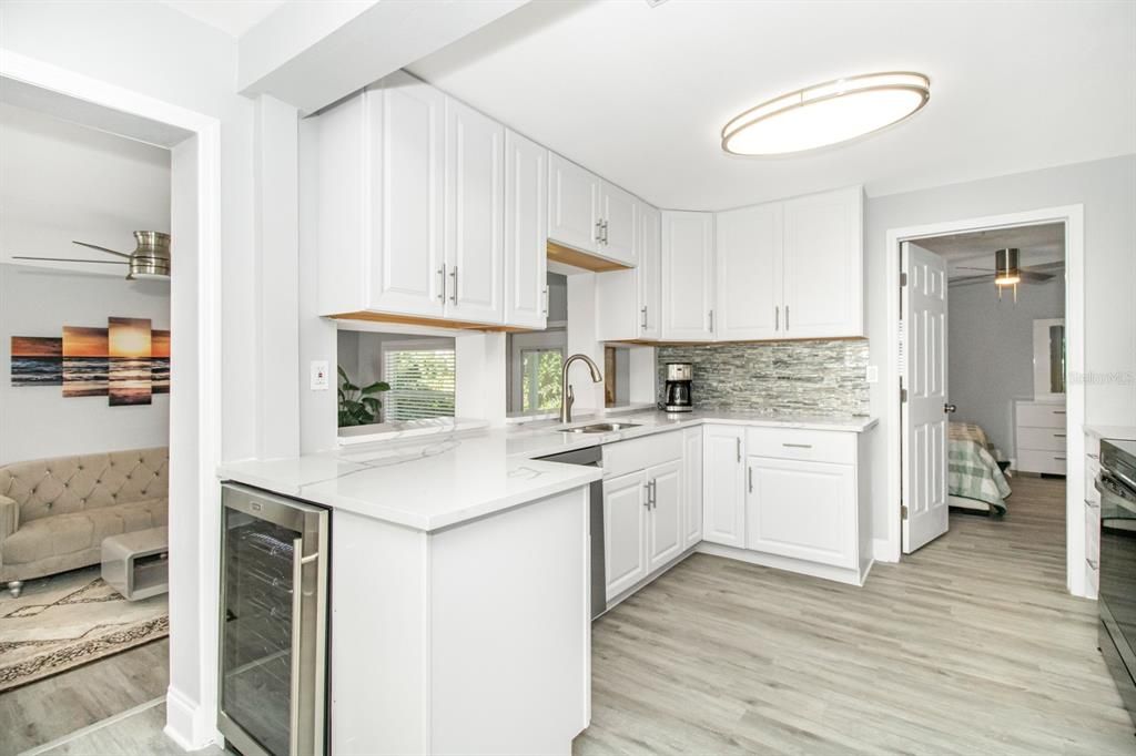 The kitchen is a chef's dream with luxurious QUARTZ countertops, a COFFEE BAR AREA with a PREMIUM WINE/BEVERAGE COOLER, STAINLESS STEEL SAMSUNG APPLIANCES, new cabinets with a lazy susan corner cabinet, LED lighting, new sink and fixture, new garbage disposal, and custom tiled backsplash.