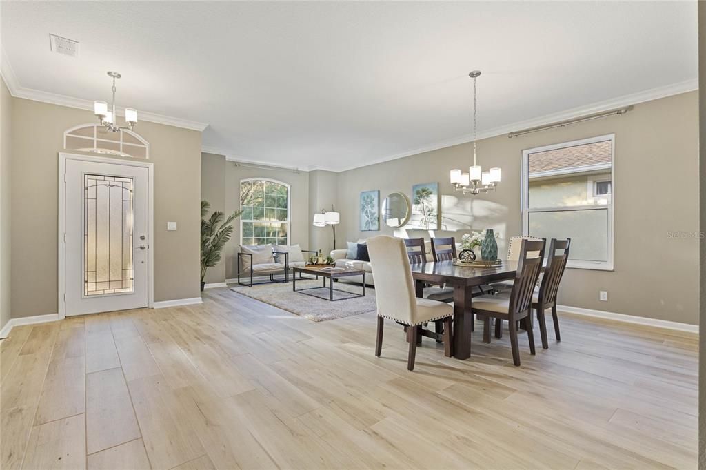 Living/Dining room combo w/ porcelain tile floors, crown molding & leaded glass front door