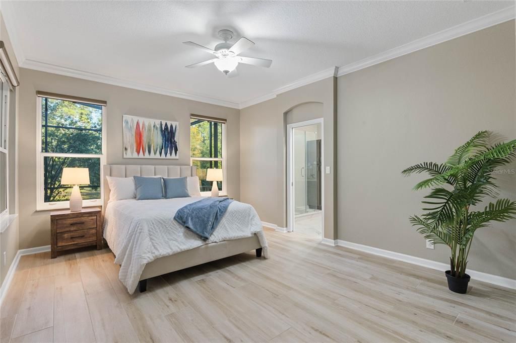 13' x 16' Primary Bedroom w/ porcelain tile floor, crown molding & a ceiling fan