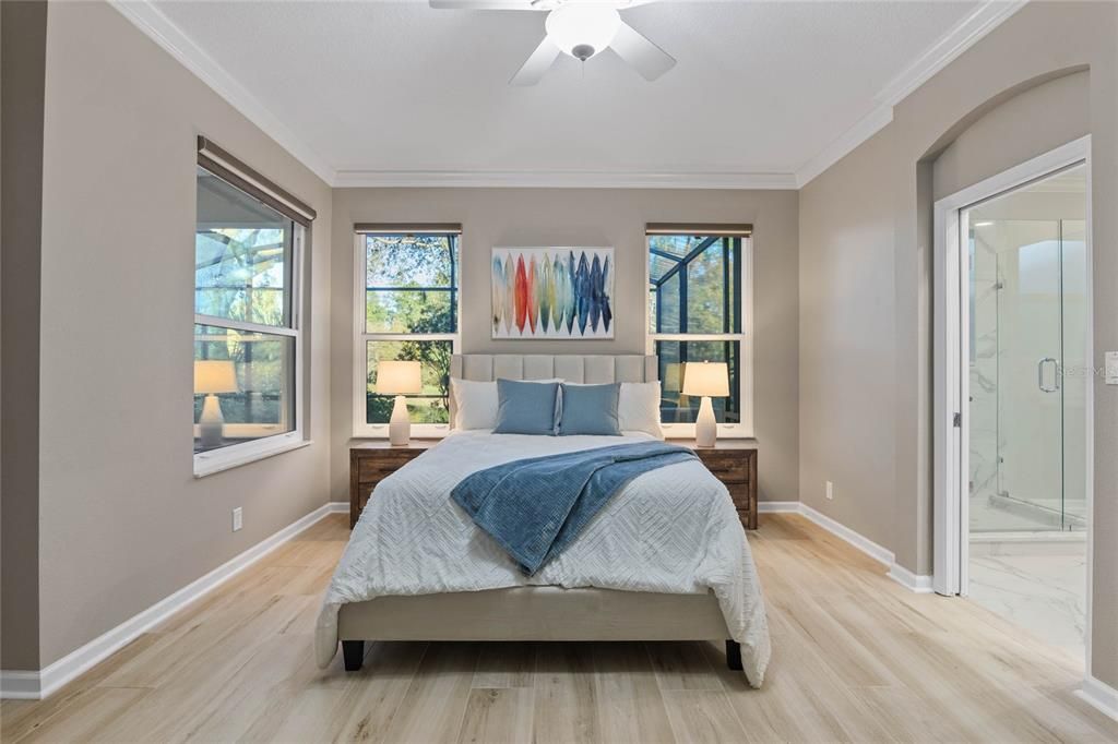 Primary Bedroom w/ several double pane windows for natural light & a pocket door to en suite bathroom