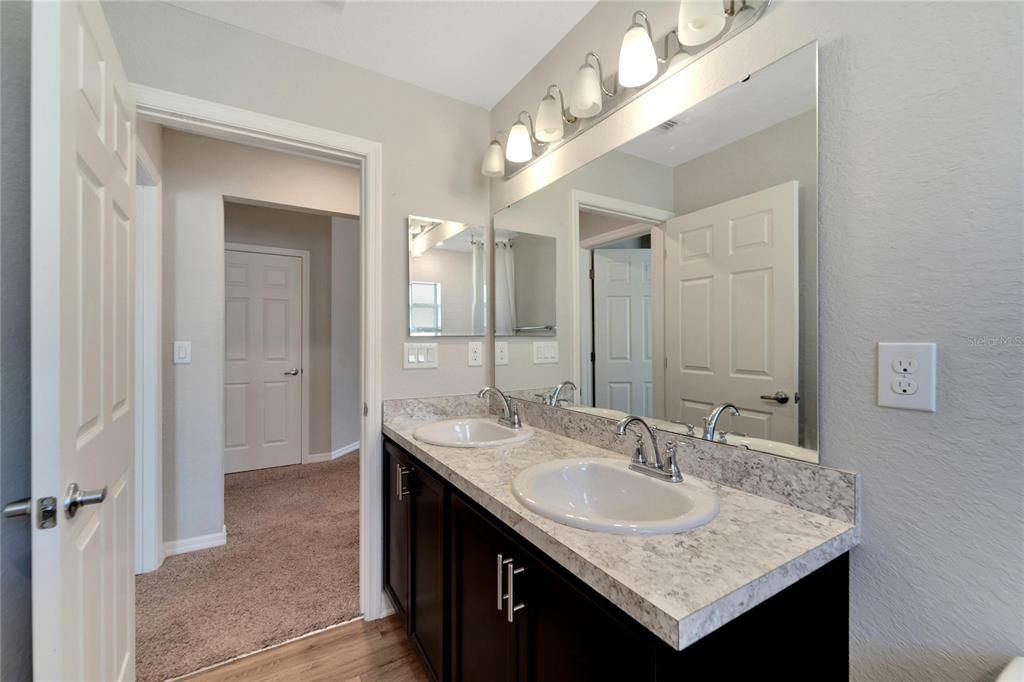 Hall bathroom with dual sinks and tub with shower