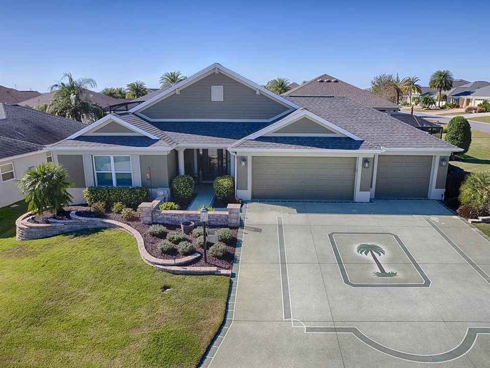 LOVELY CUSTOM LANDSCAPING WITH STACKED ROCK WALL, AND CONCRETE COATED DRIVEWAY.