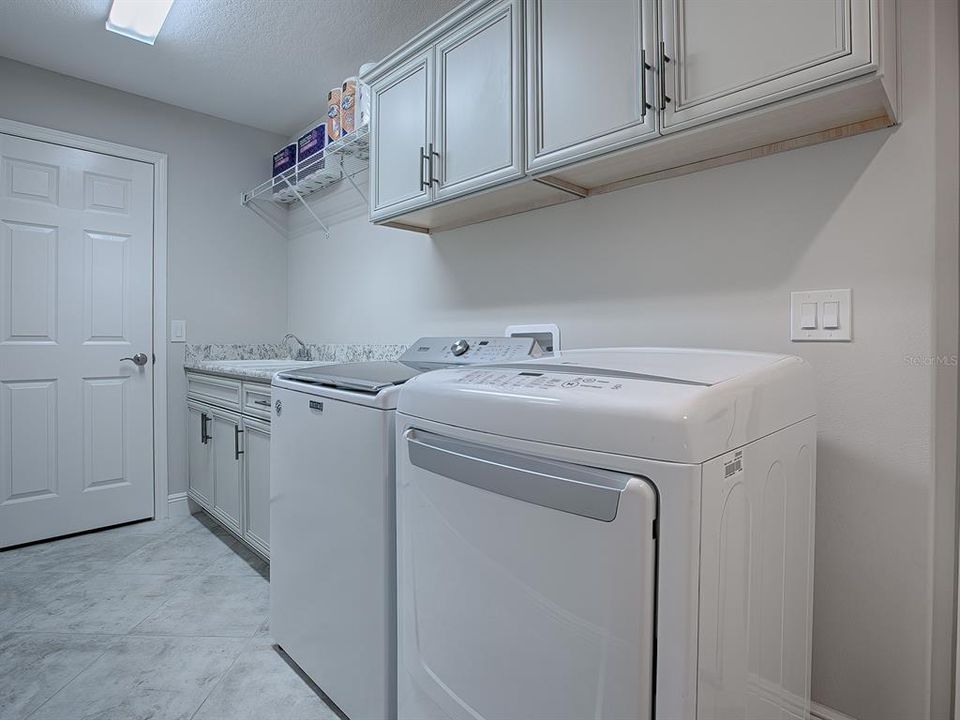 SPACIOUS LAUNDRY ROOM HAS A BUILT-IN SINK, EXTRA CABINETS, STORAGE RACK, AND A FULL CLOSET PANTRY. WASHER AND DRYER DO CONVEY WITH THE HOME.