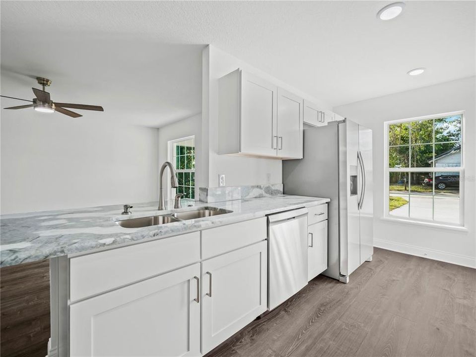 Kitchen has double sinks overlooking living room, with modern faucet, soap dispenser and push-button disposal.