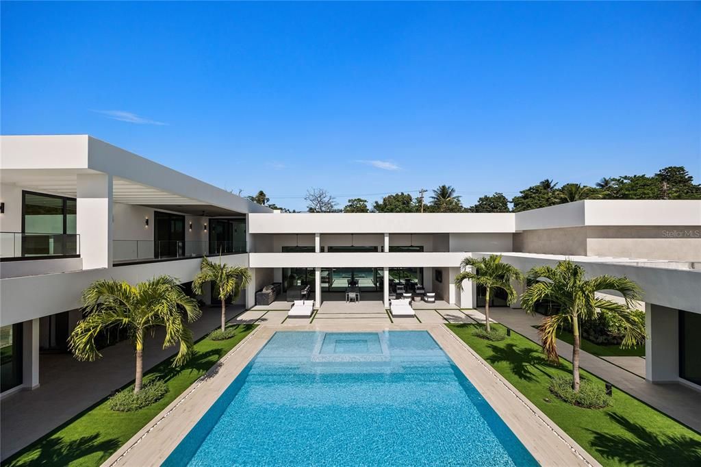 Stunning interior courtyard featuring a vertical plant wall, a serene waterfall jacuzzi, and a sparkling pool, allowing abundant natural light to flood nearly every room