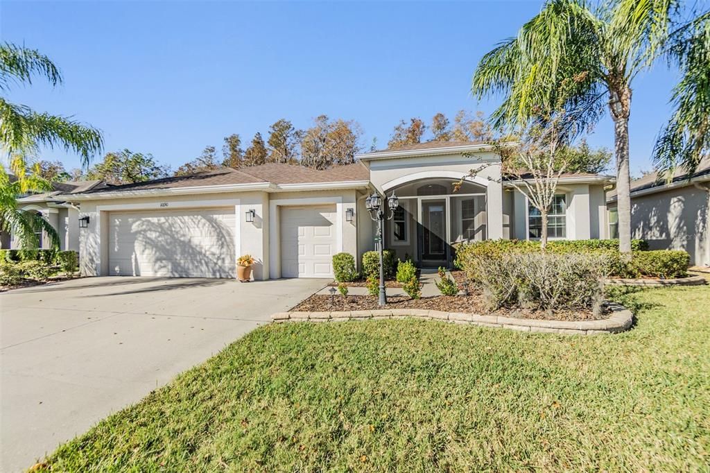 Tropical palms frame the home with paver landscaped beds and lantern for great curb appeal.