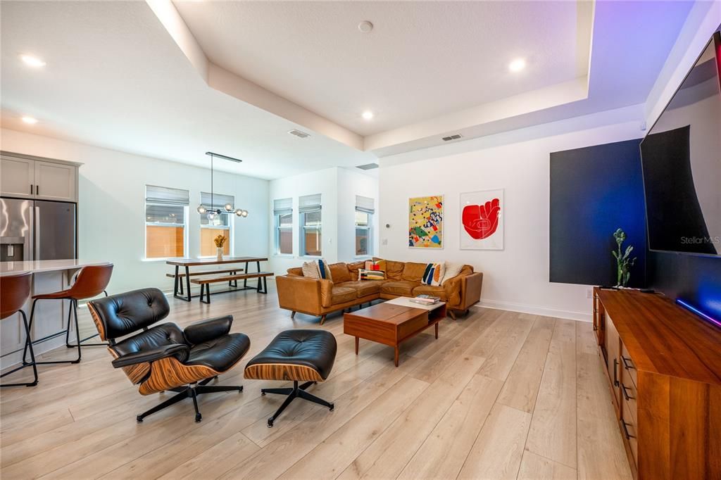 Follow the natural flow into the open living, dining and kitchen, another beautiful space highlighted by a lovely tray ceiling, multiple windows, built-in features and recessed lighting illuminates the space.