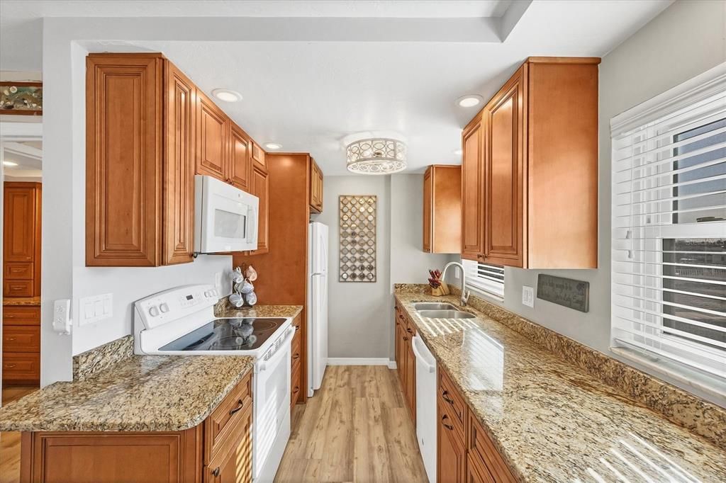 Kitchen is highlighted with granite counters & wood cabinetry