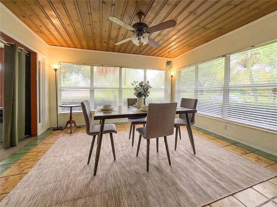 Dining room with tongue & grooved wood ceiling and 2 walls of windows.