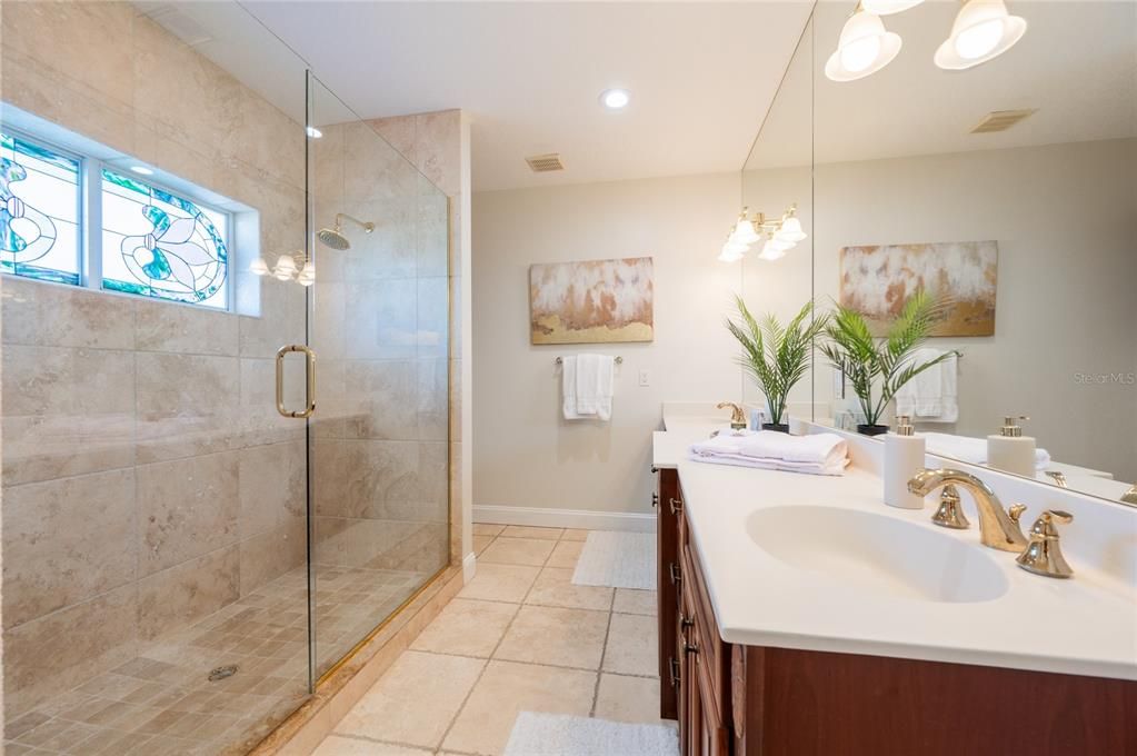 Primary bathroom has large shower and decorative stained glass windows