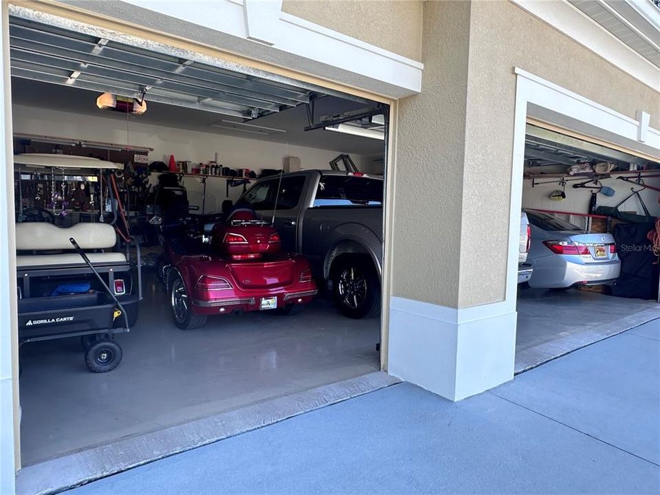 Gulf cart and 3-wheel motorcycle on left side of garage with plenty of room to walk around