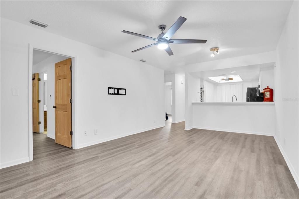 Better view of living/dining area, hallway to front bedroom, laundry in hall on left and large set of shelves, then to bathroom