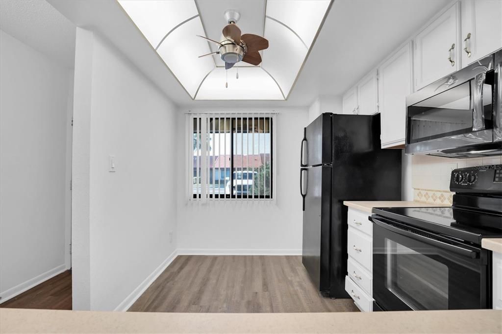 From dining counter into the kitchen. Window looks out front through the front porch area. Little hallway to left goes out the front door