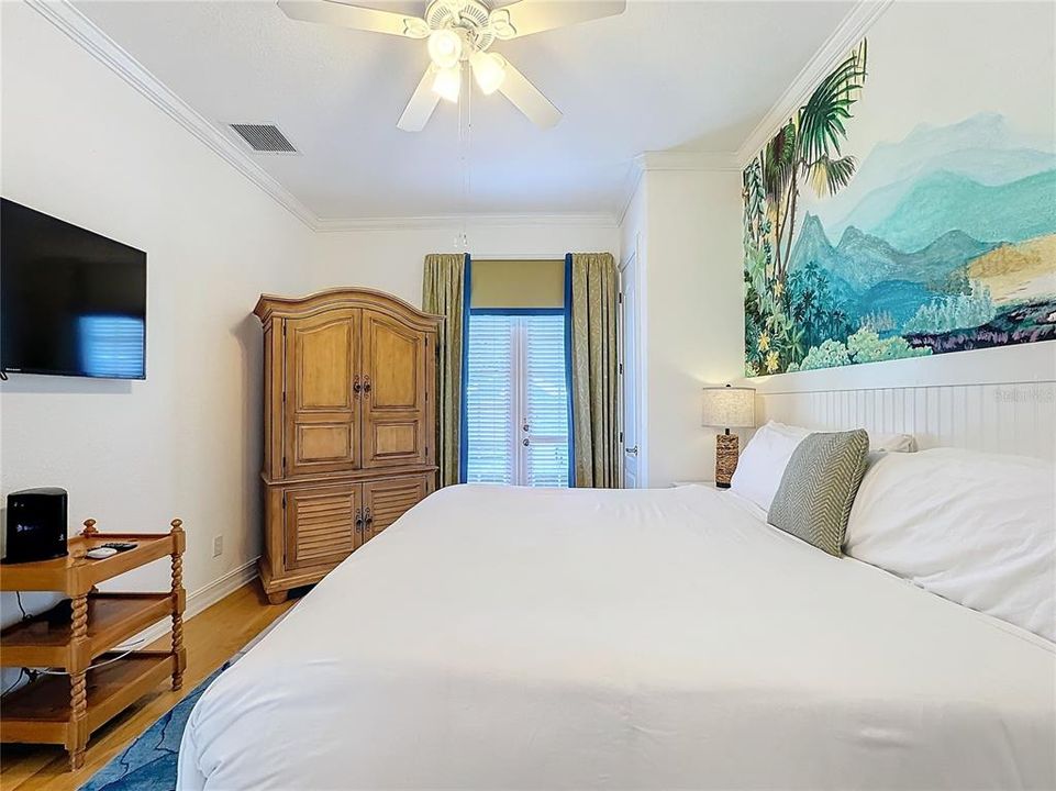 The bed, positioned directly below the mural, is a cozy, inviting space. Its crisp white linens and plush pillows create a contrast with the vivid colors of the mural, enhancing the sense of tranquility.