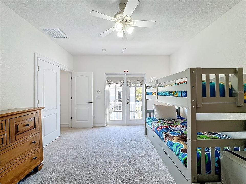 The room is bright and airy, with soft, neutral walls that create a calm backdrop for the playful, yet functional furniture. The bunk beds, a sturdy wooden frame, are positioned against one wall, with themed linens. The top bunk has a simple ladder for easy access, while the lower bunk offers a more accessible sleeping area.