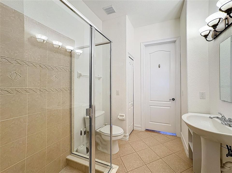 The guest bathroom is a functional space with an entrance from the living room or the downstairs bedroom.  A sleek pedestal sink sits at the center of the room, its simple design offering a clean and open feel.