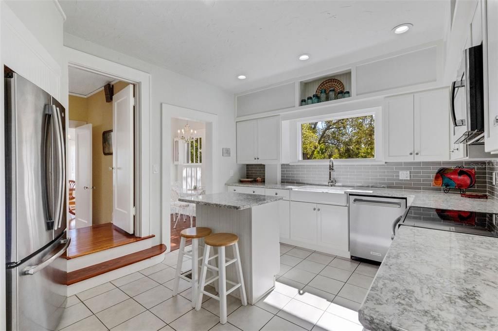 Classic white cabinets, farmhouse sink, and subway tile backsplash complement the timeless style of the home; stainless steel appliances seamlessly provide modern convenience for the cook