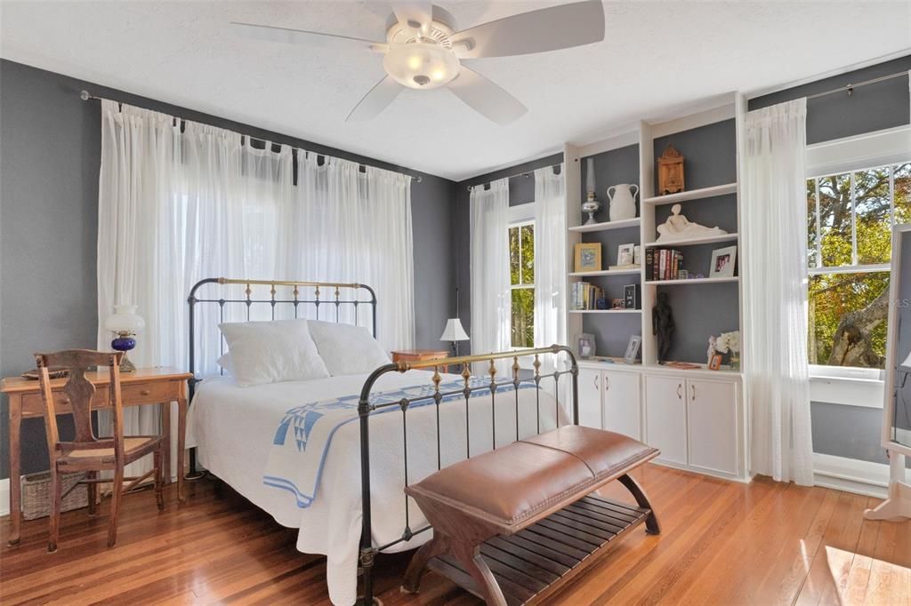 This primary bedroom is a restful retreat offering built-in bookcases, a fan to cool your nights, and scores of windows to bid you Good Morning!