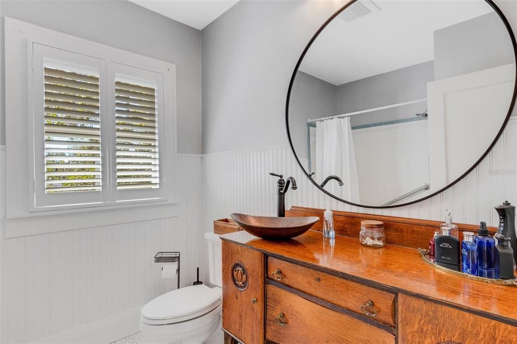 The upstairs bath has been updated to feature white wainscoting and this one of a kind vintage custom vanity with copper vessel sink