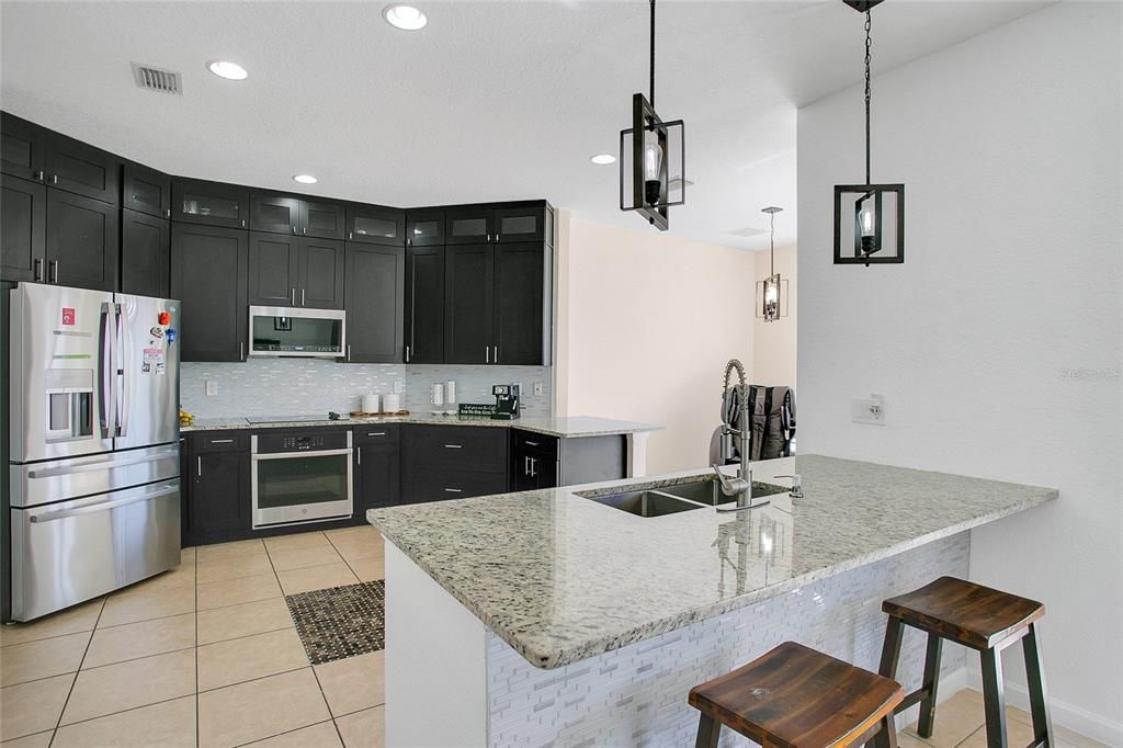 Modern kitchen featuring stainless steel appliances, ample cabinet space, a convenient breakfast bar, and direct access to the dining and living areas.