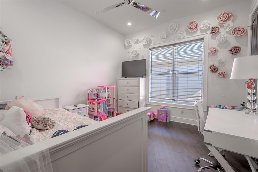 The 6th bedroom features a modern ceiling fan, neutral tones, laminate flooring and a walk-in closet.