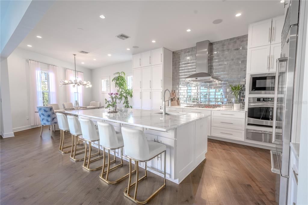 A spacious island with marble countertops is perfect for meal prep, casual dining, or casual dining. Sophisticated dining: a large eat-in dinette area with a chandelier completes this elegant kitchen layout.