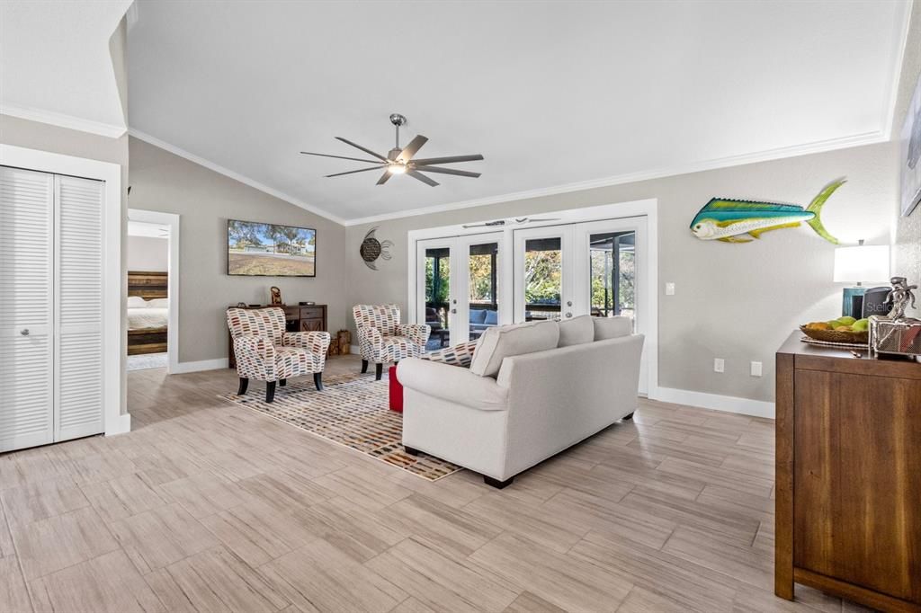 Living Room with Double French Doors to Screen Room with Heated Pool and Lounge Area