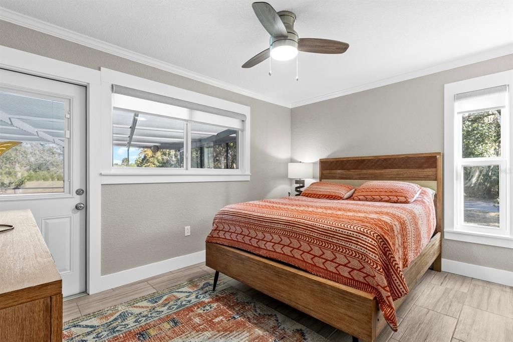 Guest bedroom in rear of house with door to outdoor living area, screened with heated pool