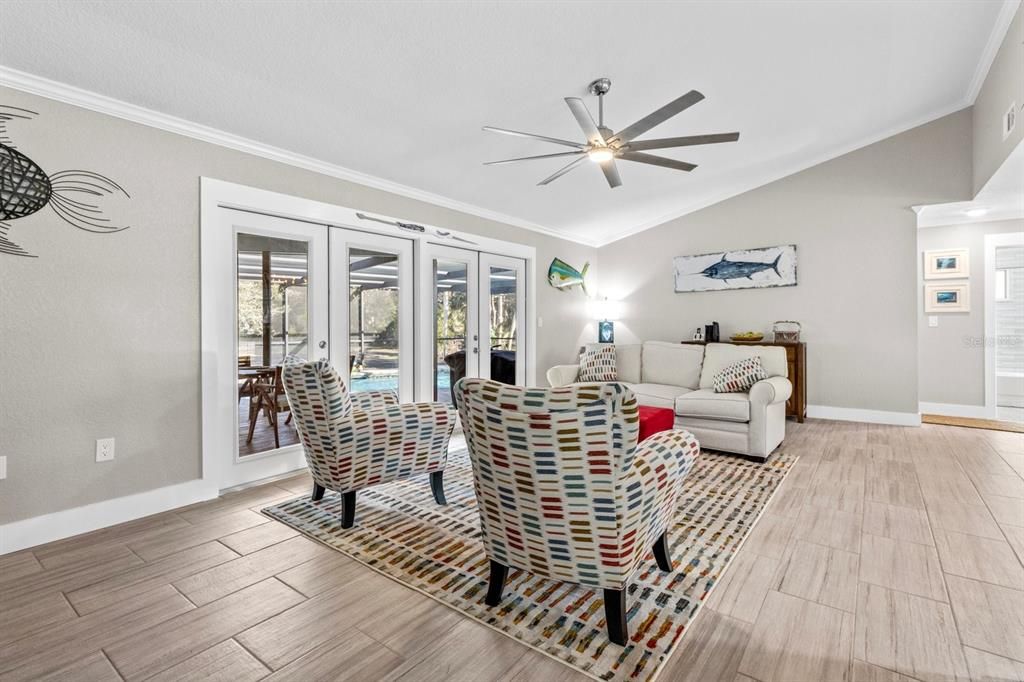 Another angle of living room with french doors to outdoor living space, screened with heated pool