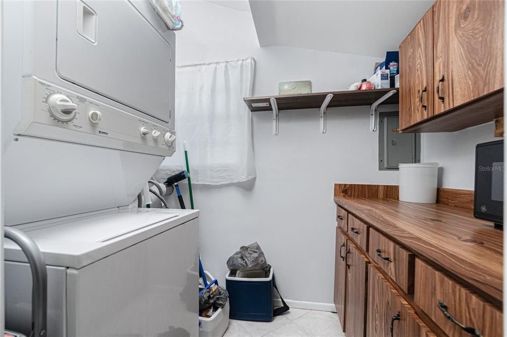 The inside utility room features built in cabinetry with lots of storage and stack washer and dryer.