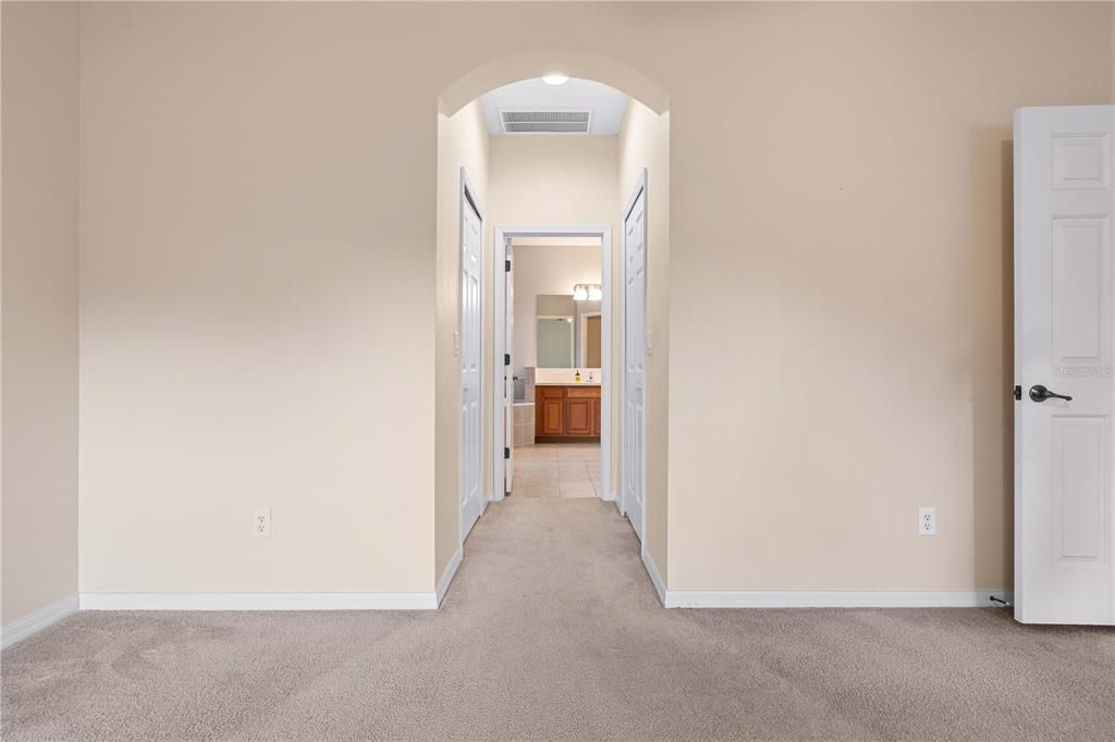 Primary bedroom view of  dual closets and primary bathroom