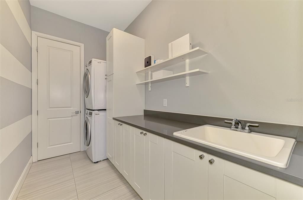 Large laundry room with added storage and utility sink.