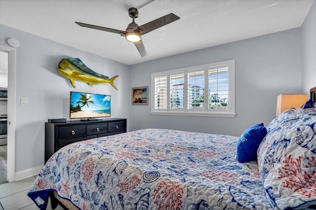 spacious room with 5 in baseboards, plantation shutters and a ceiling fan