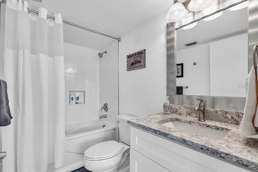 guest bath has a beautiful tub shower combo and quartz vanity top