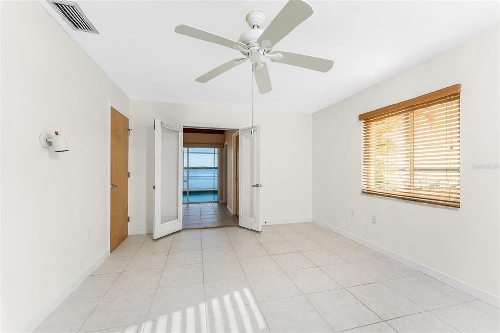 Primary bedroom features side window & french doors to pool