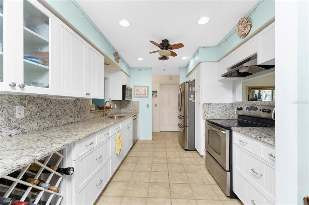 Updated galley kitchen features raised face cabinetry and granite countertops