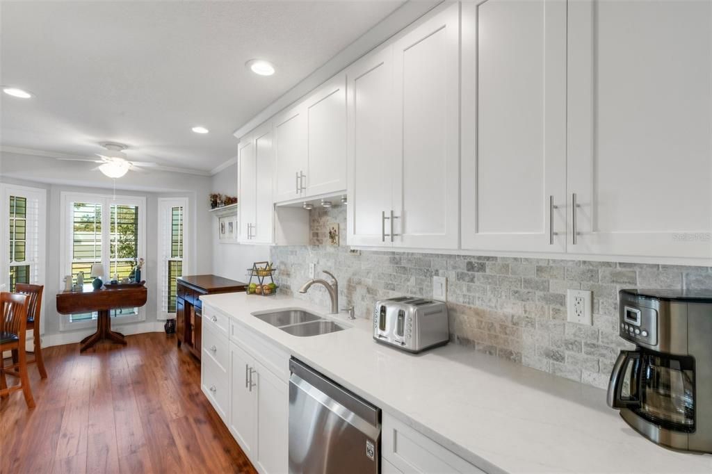 Kitchen updates include raised ceiling with recessed lighting, solid wood cabinets, quartz countertops, & travertine backsplash~