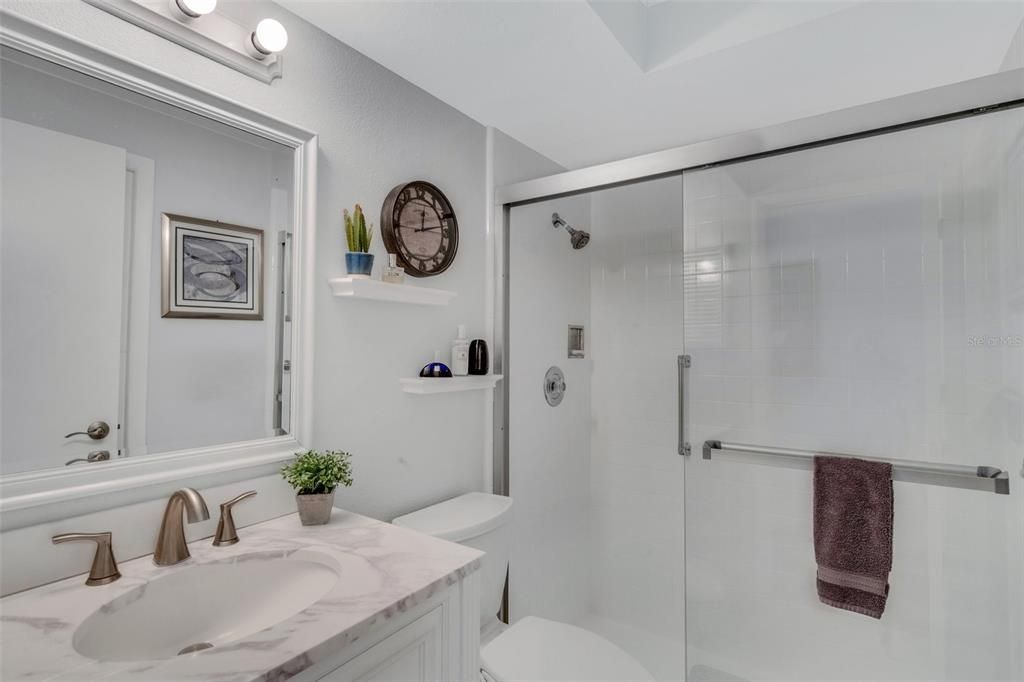 Updated hall bath with newer lighting, fixtures, marble countertop, and walk-in shower~