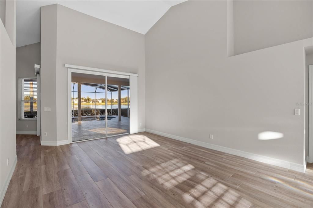 Living Room:Relax in the spacious living room with stunning central lake views, vaulted ceilings, and a seamless flow to the outdoor oasis.