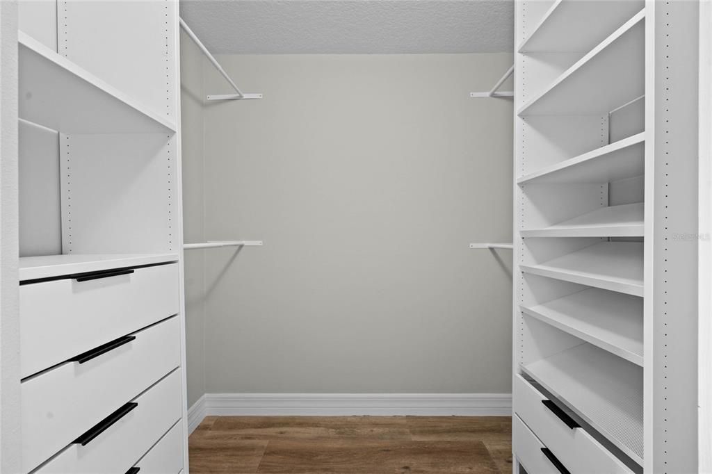 Dual primary bedroom closets with built in storage system.