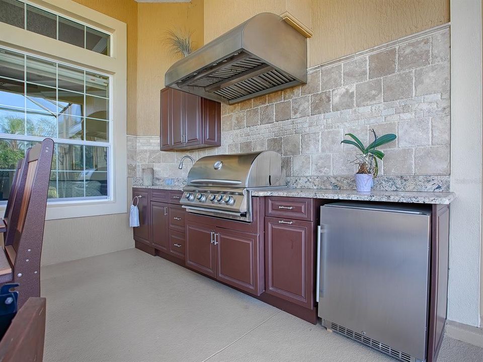 LOVELY TILE WALL, GRANITE COUNTERTOPS, BLAZE GAS GRILL AND HOOD, REFRIGERATOR AND SINK AND BAR AREA!